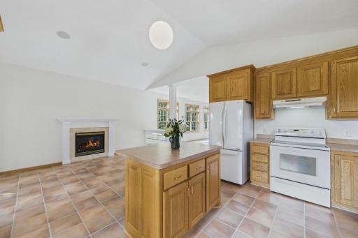 Another view of the kitchen highlights the center island, vaulted ceiling and open connection to the surrounding living spaces.