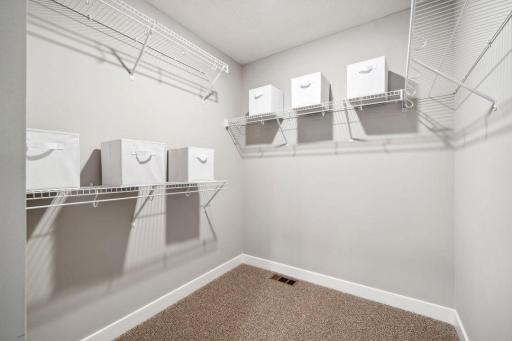 An extension of the primary suite, this private and spacious bathroom contains a double-vanity, a separate shower and tub, a private water closet, plus two walk-in closets. Photo is of previously built model home, finishes, selections will vary.