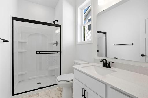 This bathroom is discreetly located down a hallway off the foyer, offering access to a single vanity and glass-enclosed shower.