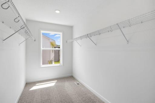 The walk-in closet features a window to bring in ample natural light and mesh-wire shelving to easily store growing wardrobes