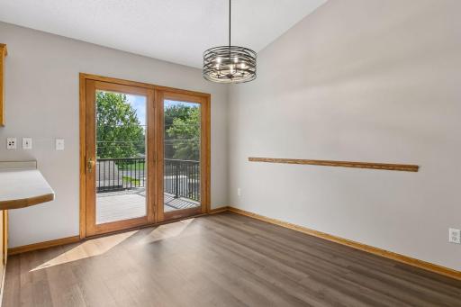 Warm and welcoming dining room with brand new light fixture and flooring (2026) and walkout to deck.