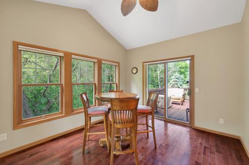 Bright & inviting 4 seasons porch featuring soaring vaulted ceilings, rich hardwood flooring, & expansive windows that showcase beautiful wooded views. This welcoming space is filled with natural light and offers direct access to the spacious deck,
