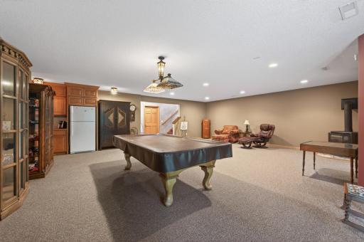 This expansive recreation room features plush carpeting, recessed lighting, a cozy fireplace, and direct access to the patio and backyard through multiple sliding glass doors