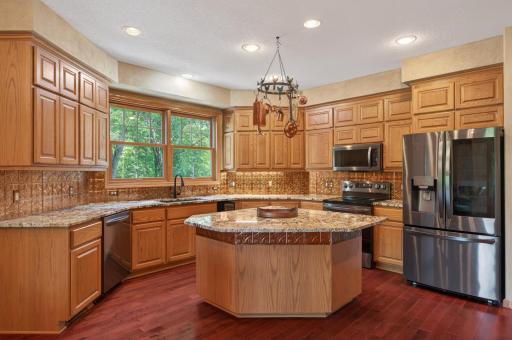 Beautifully appointed kitchen designed for both everyday living and entertaining. Featuring abundant custom cabinetry, granite countertops, a spacious center island, stainless steel appliances, and rich hardwood flooring