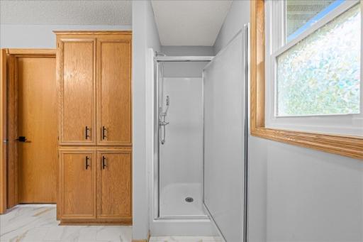 View of upper level full bath shower and cabinets