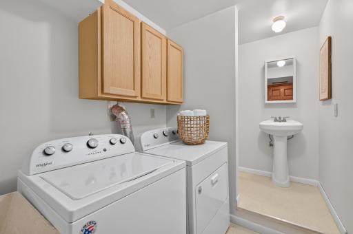 Clean and well-maintained lower-level laundry room with sink and storage. Offering a bright and functional space for everyday convenience
