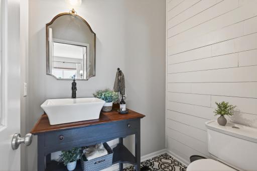 Remodeled main-floor powder bath featuring designer flooring, shiplap accent wall, updated vanity, and vessel sink.