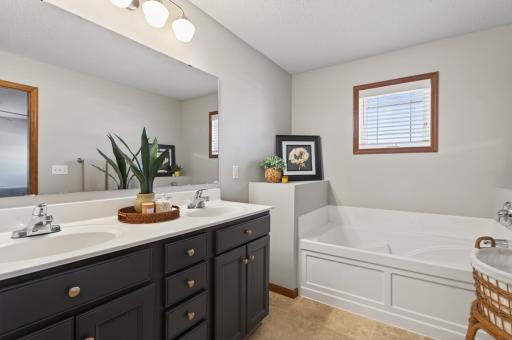 Primary bathroom with dual-sink vanity, soaking tub, and separate shower.