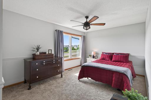 Spacious secondary bedroom with large window and updated ceiling fan.