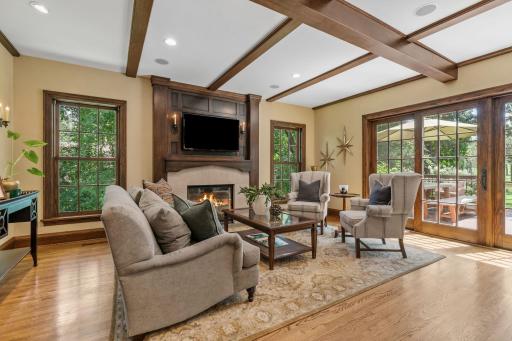Great room adjoins the kitchen with exposed beams, built-in ceiling speakers, and a gas fireplace featuring a beautifully crafted mantel and limestone surround
