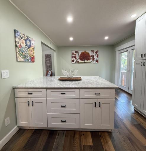 The extra-large kitchen island features storage on both sides, a marble top, and ample space for bar stools, making it ideal for easy entertaining.
