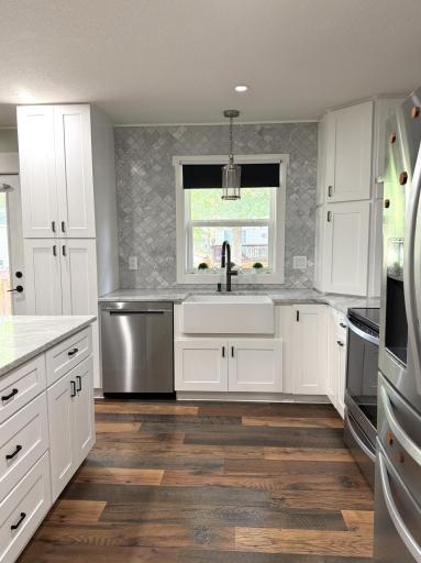 The kitchen features a porcelain farmhouse sink, stainless steel appliances, a newer dishwasher, recessed lighting, and a vented hood, creating a bright and functional space for everyday living and entertaining.