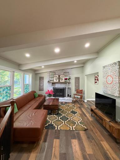 The living room offers vaulted ceilings, recessed lighting, a decorative wood-burning fireplace, luxury vinyl plank flooring, and fresh paint, creating a warm and welcoming setting.
