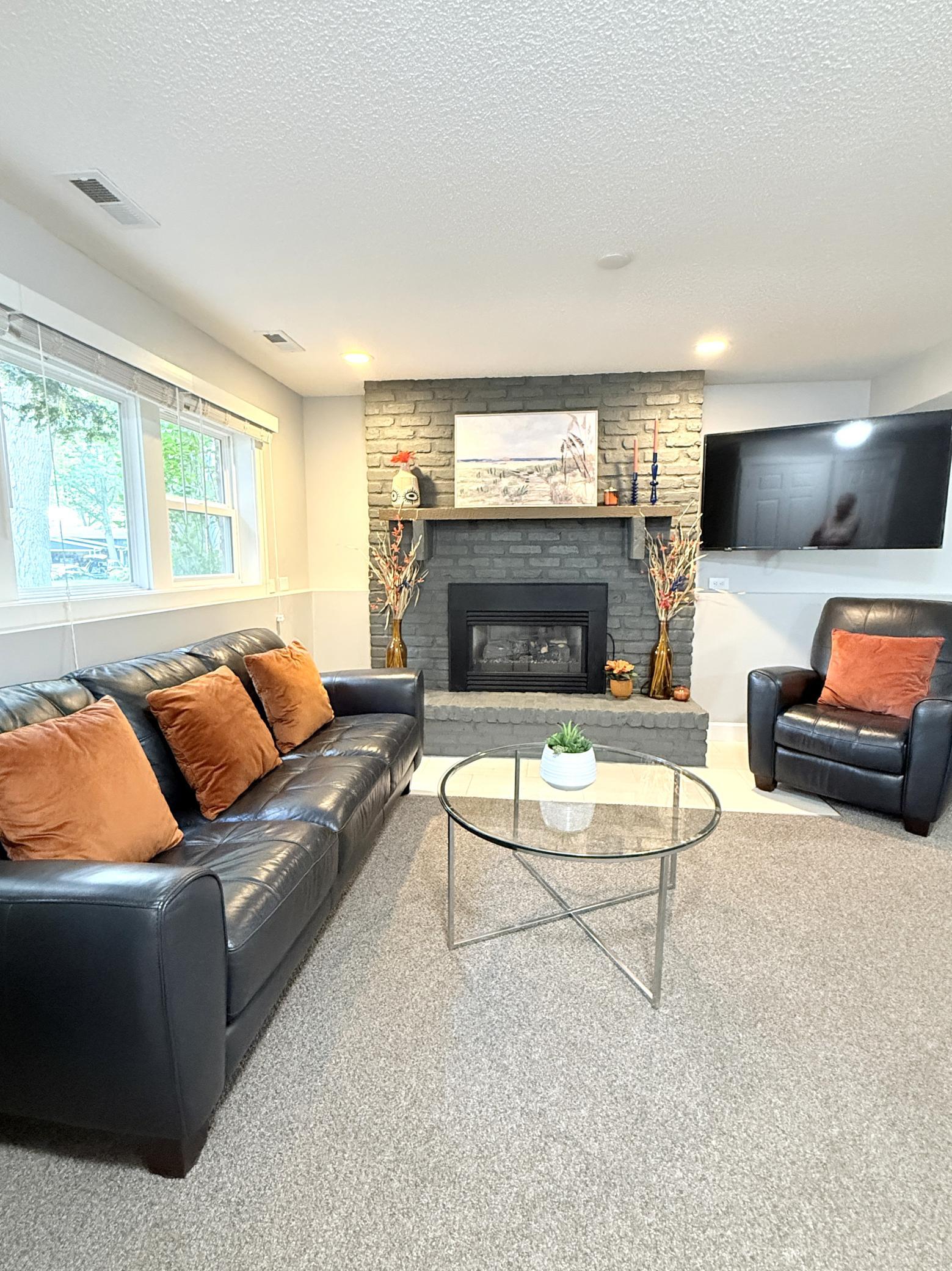 The lower-level family room offers a warm and inviting retreat with abundant natural light and a cozy gas fireplace. This bright and comfortable space is perfect for relaxing, entertaining, or gathering with family, creating a welcoming atmosphere.