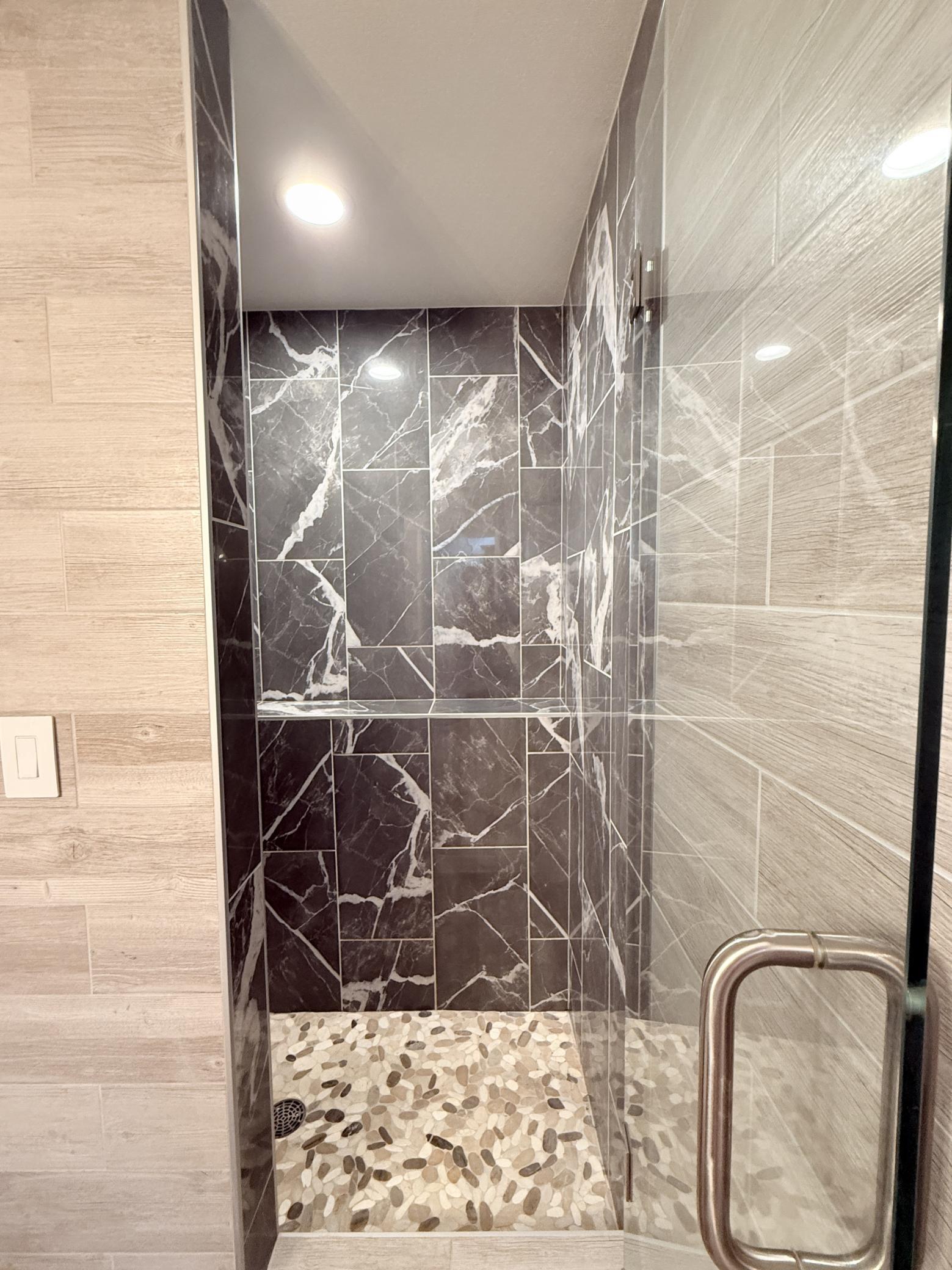 Walk-in tiled shower with glass door.