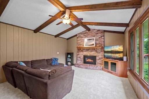 Stunning vaulted family room highlighted by exposed wood beams, paneled walls, a cozy fireplace. This may be your favorite relaxation spot!