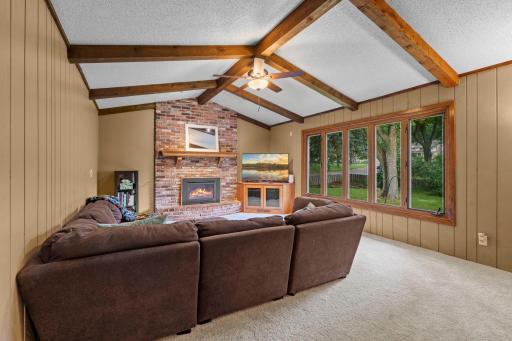Multiple gathering spaces on the main level include a welcoming living room and a stunning vaulted family room highlighted by exposed wood beams, paneled walls, a cozy fireplace.