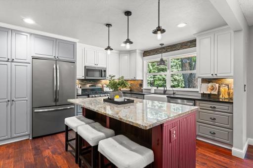 Beautifully remodeled kitchen includes ample cabinet space, granite countertops, center island, backsplash, and stainless steel appliances