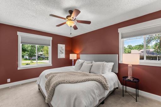Bright primary suite with windows on either side and a ceiling fan for comfort
