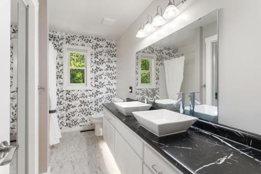 Upper-level full bathroom, complete with 2 sinks, large mirror, and well-lit even with under glow cabinet lighting