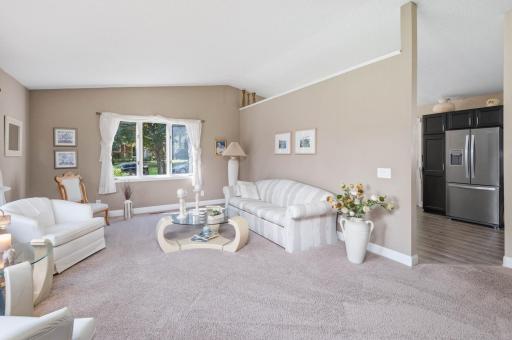 The updated carpeting, white window trim and tall white baseboards complete the room. One wall looks like it could potentially be opened up.