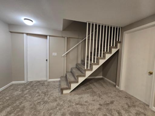 Family or recreation room has new carpet and stairs from upper level. Door to the right goes to laundry or furnace area
