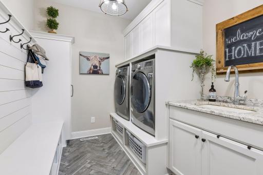 The spacious laundry room includes plenty of cabinets for storage and a handy sink.