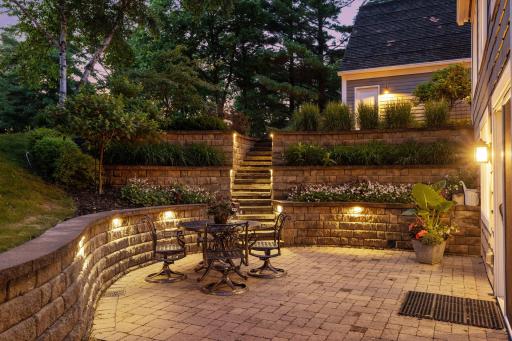 Lush perennial plantings and extensive landscape lighting create a secluded patio experience right at home.