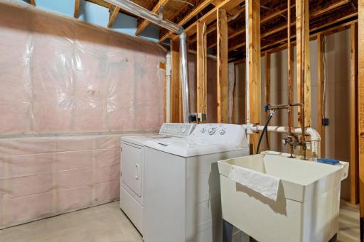 Convenient lower-level laundry area features a utility sink, newer washer, and easy access to the home's mechanicals.