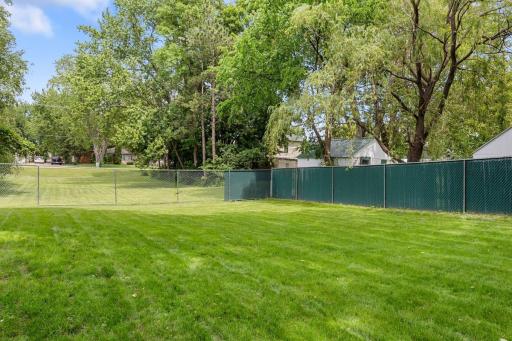Another perspective of the generous fenced backyard, where mature trees and nearly a quarter acre of green space create a wonderful setting.