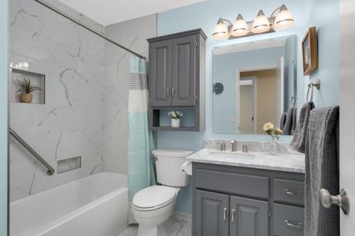 Beautifully remodeled upper-level bath showcases stone-inspired tile, updated cabinetry, and modern fixtures.