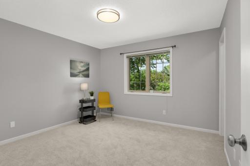 Spacious upper-level bedroom with a large window and serene backyard views.