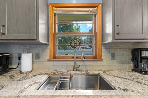 Functional kitchen sink area with a large window offering backyard views and updated fixtures.