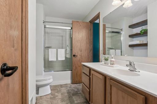 Main floor full bath with large storage closet and custom wood shelving