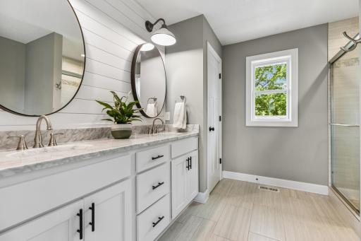 Well-appointed primary bath featuring dual sinks, marble surfaces, and modern finishes.