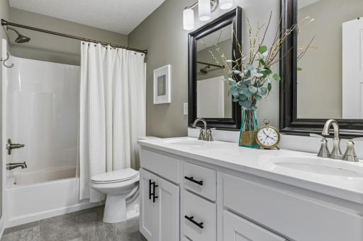 Upper level full bathroom with dual sinks, quartz countertops, and updated finishes.