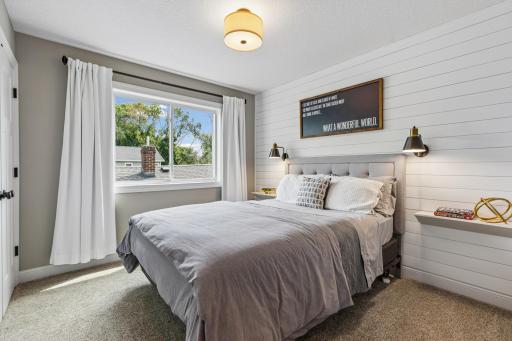 Comfortable bedroom highlighted by a shiplap accent wall and natural light.