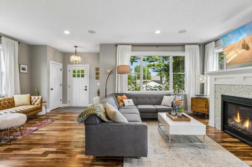 The living room combines comfort and style with a tiled fireplace, built-in media cabinet, and rich acacia wood floors.