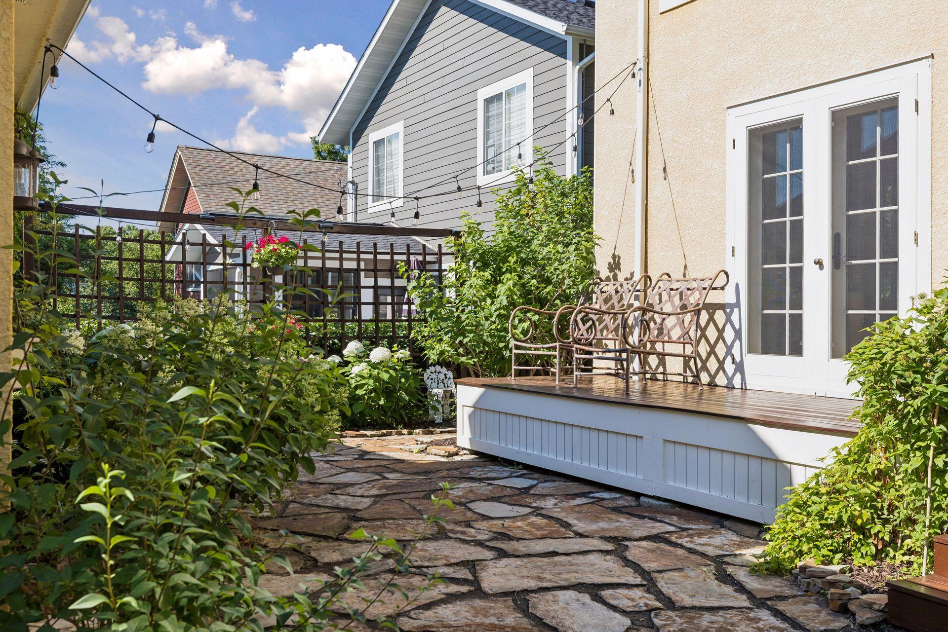 Patio space and deck waiting for new furniture to entertain. Surrounded by perennial gardens and landscape lighting.