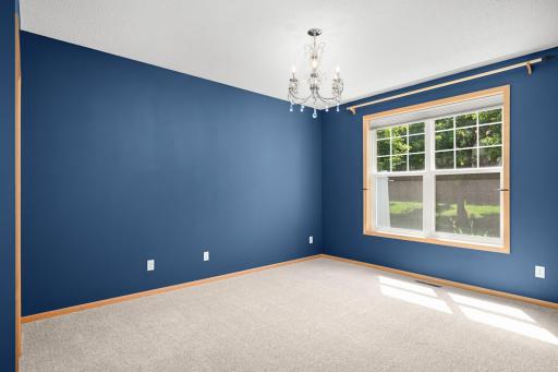 The main floor primary is flooded with natural light, features a beautiful chandelier and brand new carpet.