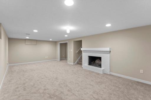 The entire lower level was carpeted in 2026. The smaller doors on the far wall open to the crawl space beneath the formal DR.