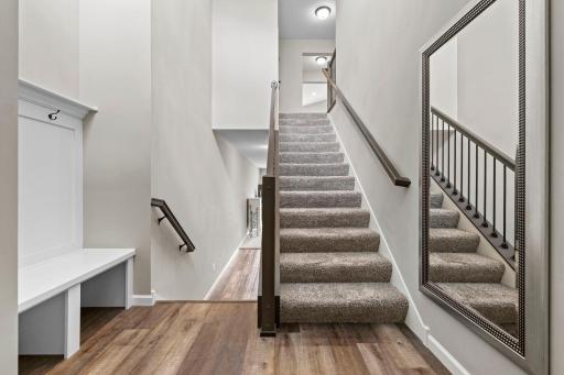 Foyer with Built-In Custom Bench with cubbies and hooks, coat closet, LVP flooring, and iron rod balusters highlighting the space.