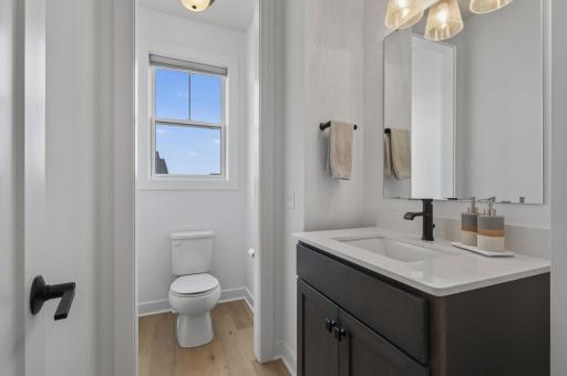 Conveniently located on the main level, this stylish powder room showcases contemporary finishes, a sleek vanity with quartz countertops, and a bright window that adds natural sunlight for guests and everyday convenience.