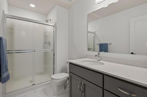 Conveniently located on the upper level, this three-quarter bathroom offers a sleek vanity, easy-care finishes, and a glass-enclosed shower.