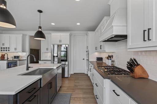 Every detail has been thoughtfully selected, from the dramatic two-tone cabinetry and oversized island to the professional-style gas cooktop and generous walk-in pantry.