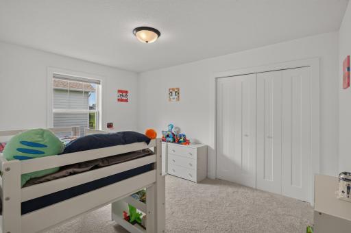 This third bedroom on the upper level showcases soft neutral tones, a large closet, and plenty of natural daylight.