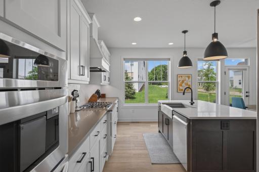 Bathed in natural sunlight, this beautifully appointed kitchen pairs sleek finishes with an inviting layout that's ideal for everything from morning coffee to holiday gatherings.