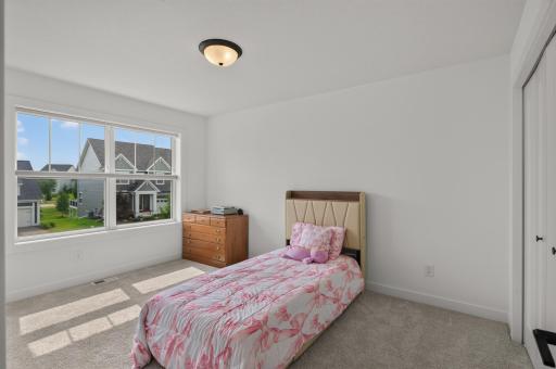 This generously sized second bedroom on the upper level features abundant natural light, soft neutral finishes, and ample space to personalize.