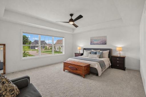 Retreat to the oversized primary suite featuring a tray ceiling, expansive picture window, and plenty of room for a king size bed, side tables, and multiple dressers.