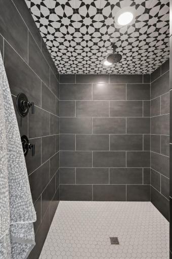 An impressive walk-in shower combines bold contemporary finishes, eye-catching geometric details, premium black fixtures, and generous space for a luxurious everyday experience.